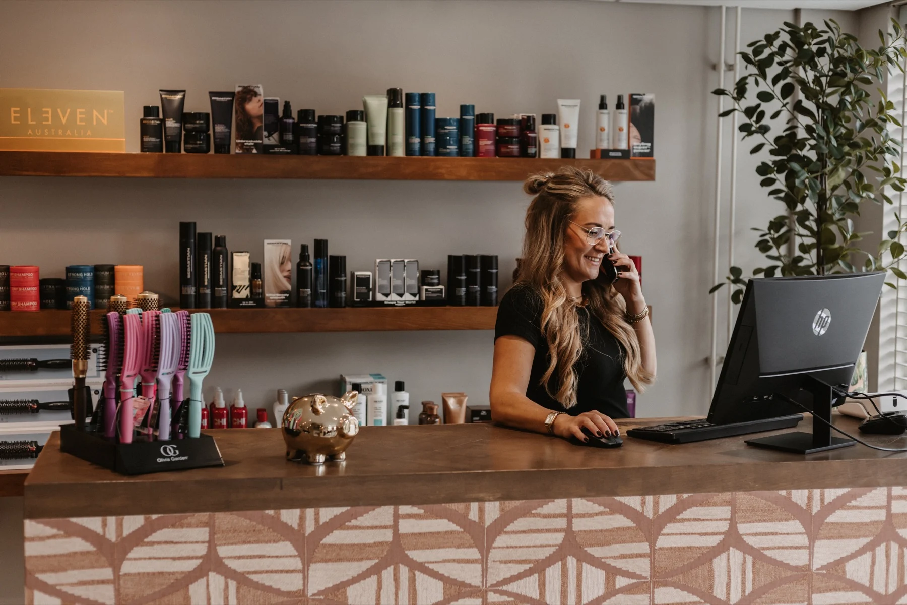 Medewerker aan de balie van LOOX Kappers met producten op de schappen