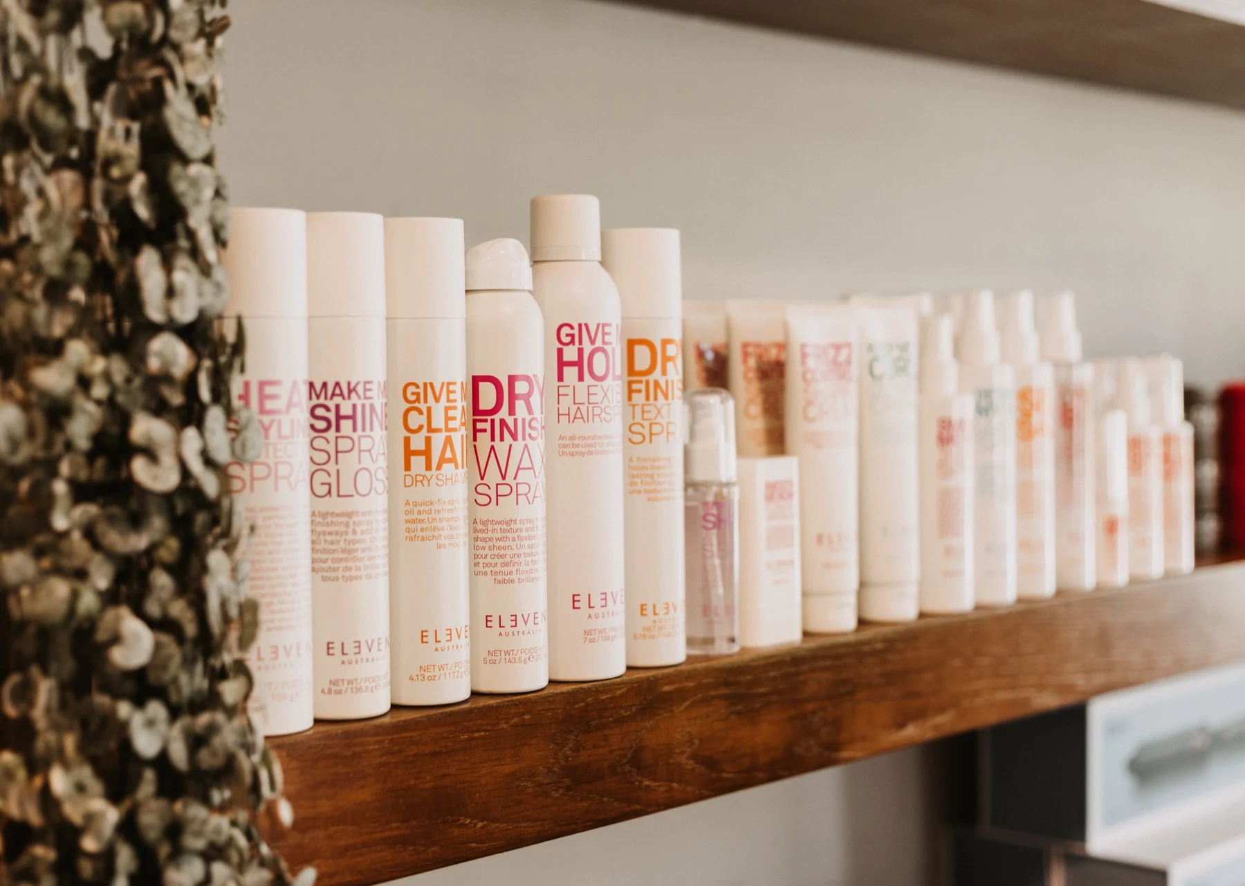 Haarproducten van Eleven Australia op een houten plank in de salon