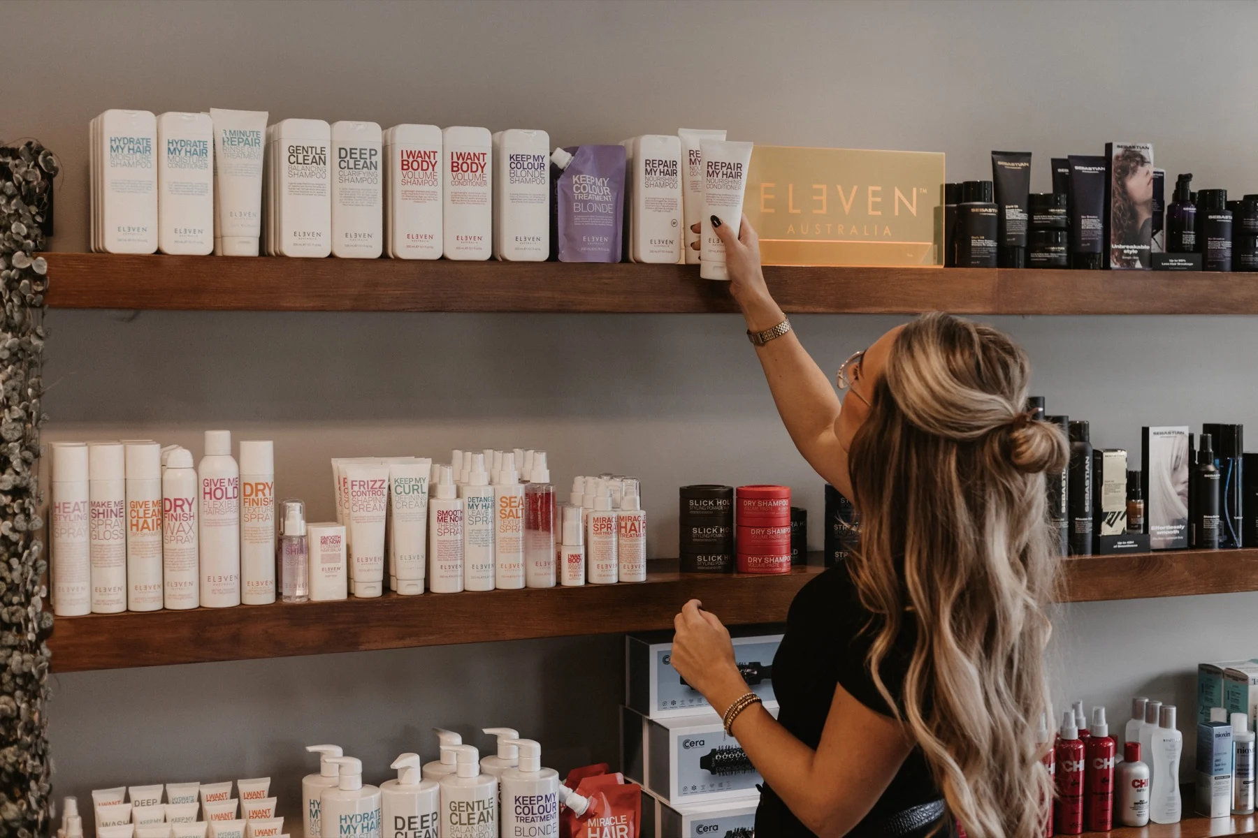 Hairstylist pakt een product van Eleven Australia uit de schappen van LOOX Kappers